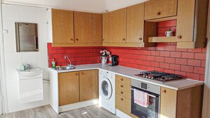 Een kleine keuken met houten kastjes, een wasmachine, een fornuis en een spoelbak.