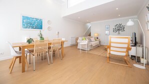 A spacious living area with a dining table, chairs, a sofa, and a large window. - Rosemary House (Tavira)