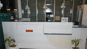 A reception desk with a marble design, a reception sign, and two potted plants. - Hotel GV Group and Restaurant (Khatoo)