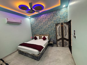 A bedroom with a bed, a ceiling fan, and a decorative door. - Hotel GV Group and Restaurant (Khatoo)