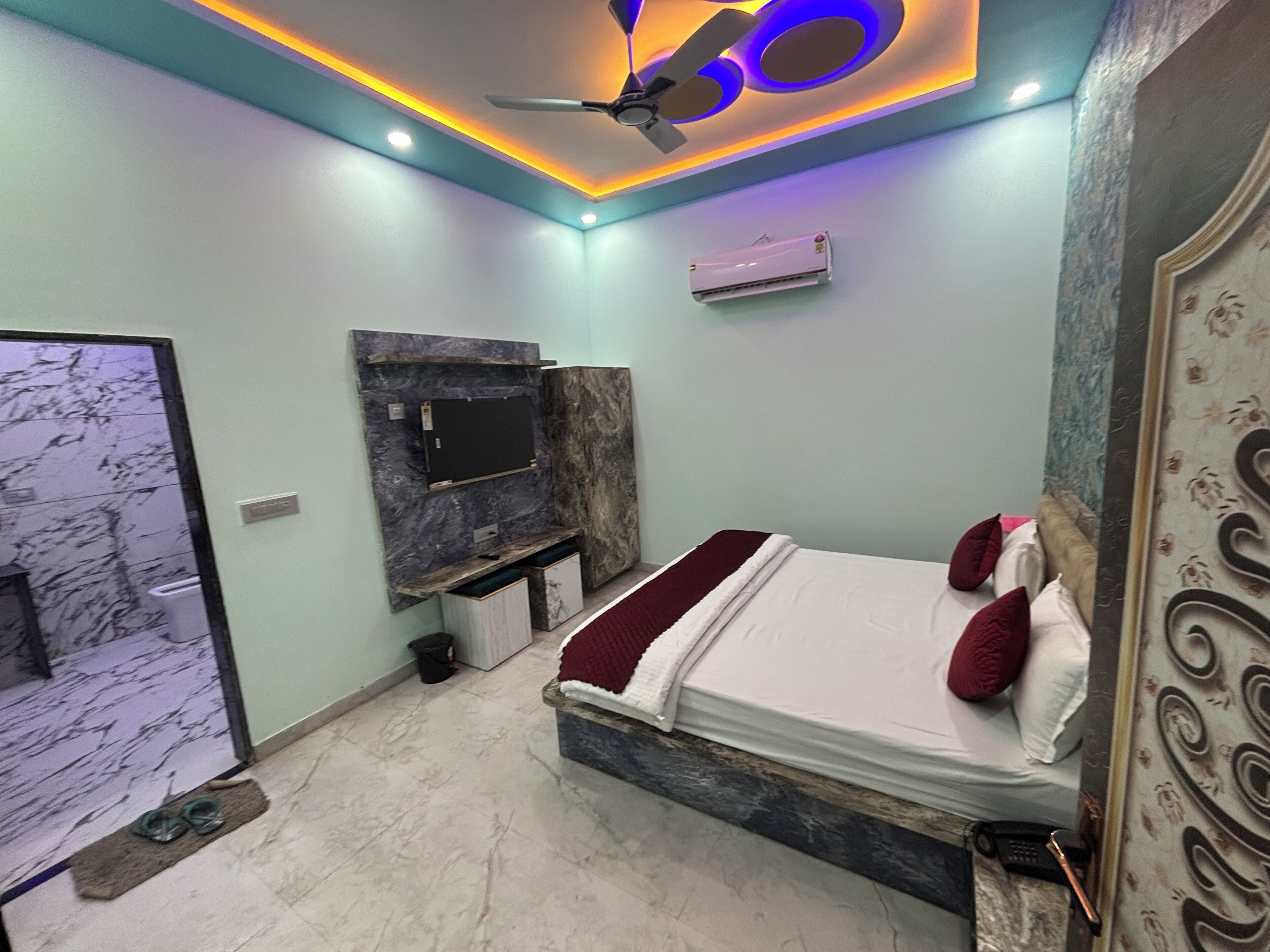 A modern bedroom with a bed, a ceiling fan, recessed lighting, a mounted air conditioner, and a marble-patterned wall.