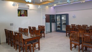 A spacious dining area with a large wooden table and chairs, an air conditioning unit, and decorative balloons on the ceiling. - Hotel GV Group and Restaurant (Khatoo)