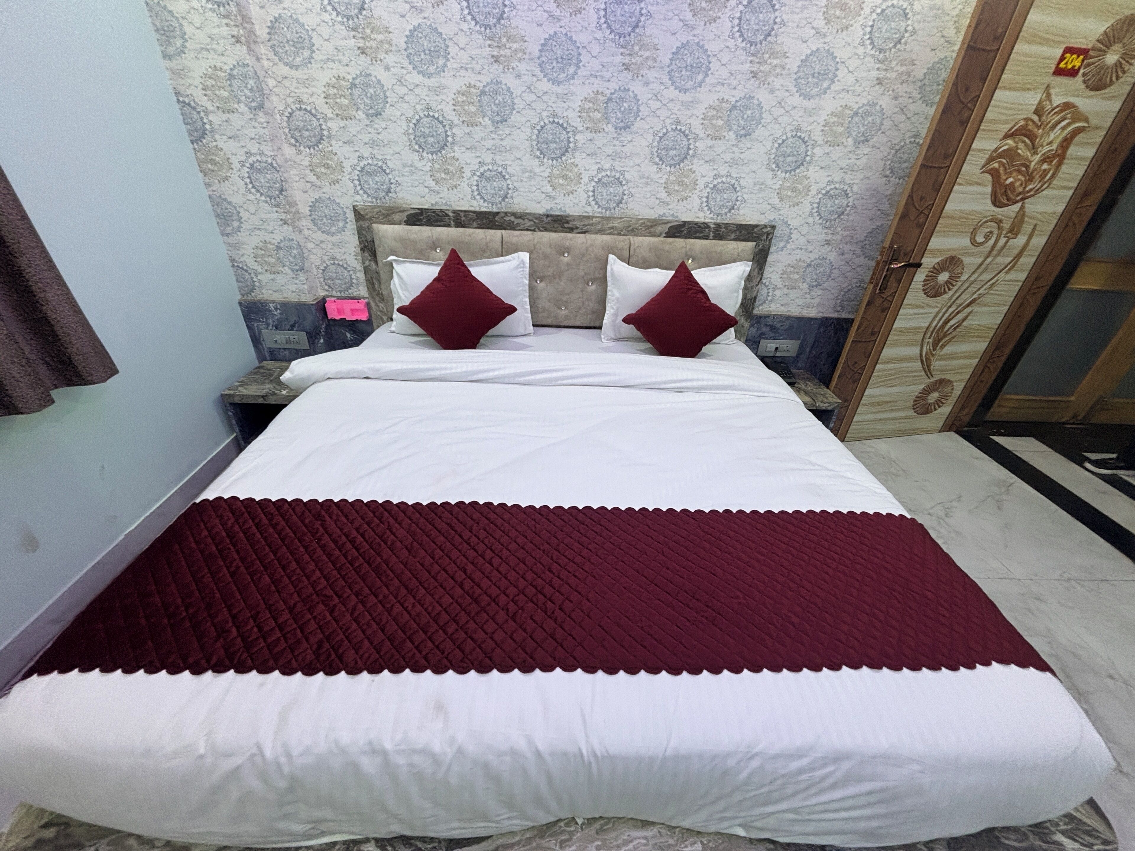 A neatly made bed with a red and white bedspread, two red pillows, and a wooden headboard.