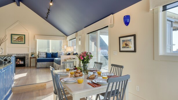 A bright dining area with a table set for breakfast, a fireplace, and a view of the city.