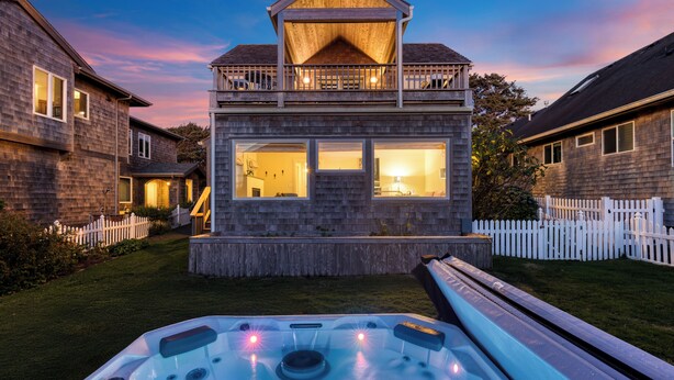 Una casa de dos pisos con un jacuzzi en el jardín delantero.