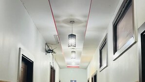 A hallway with wooden paneling on the walls, a tiled floor, and a ceiling with recessed lighting and red accent lines. - Hotel Green Lotus (Noida)