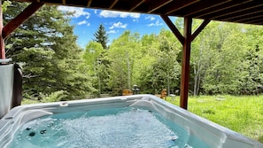 A hot tub with a wooden deck and a view of a forest. - New owner!  10 minutes from the Massif with a view of the St Lawrence River! (Petite-Rivière-Saint-François)