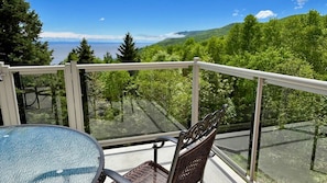 A balcony with a glass railing, a wicker chair, and a table.