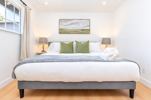 A bedroom with a bed, pillows, a blanket, a painting on the wall, and two bedside lamps. - Spacious 4BR Home Mins to Santa Clara & Tech Campuses (San Jose)