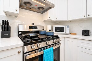 A modern kitchen with white cabinetry, a stainless steel stove, a microwave, and a toaster. - Spacious 4BR Home Mins to Santa Clara & Tech Campuses (San Jose)