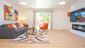 Ein modernes Wohnzimmer mit grauem Sofa, orangefarbenem Sessel und Kamin.