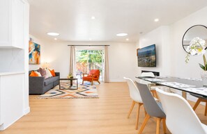 A modern living room with a sofa, coffee table, and a dining area with chairs and a table. - Spacious 4BR Home Mins to Santa Clara & Tech Campuses (San Jose)