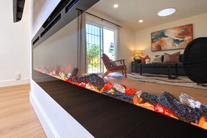 A modern living room with a fireplace, a sofa, and a painting on the wall. - Spacious 4BR Home Mins to Santa Clara & Tech Campuses (San Jose)