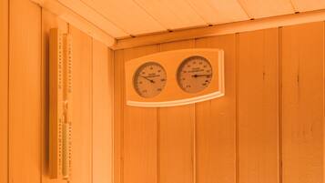 Una sauna de madera con dos termómetros que muestran la temperatura y la humedad.