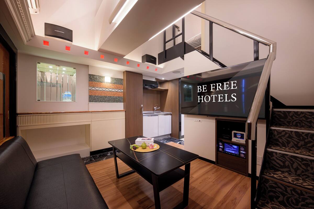 A compact hotel room with a kitchenette, a dining area, and a staircase.