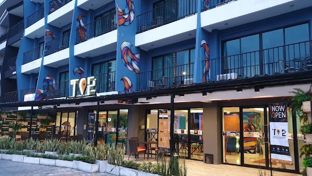 Un hôtel à la façade bleue, doté de nombreux balcons et d’une enseigne indiquant qu’il est désormais ouvert.