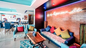 Un espace de détente moderne avec un mur en briques, des coussins colorés et un panneau lumineux au néon.