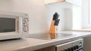 Een keuken met een witte magnetron, een messenblok en een fornuis.