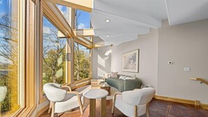 Een moderne woonkamer met een groot raam, een bank, twee fauteuils en een salontafel.