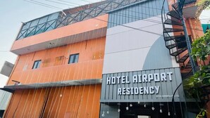 Un edificio de varios pisos con un cartel que dice 'HOTEL AIRPORT RESIDENCY'.
