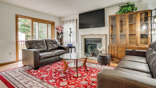 A living room with a fireplace, leather sofas, a glass coffee table, and a large cabinet. - 12 Mi to Dtwn St Paul: Extended Stay in Woodbury! (Woodbury)