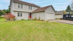 A two-story house with a red door, a garage, and a well-maintained lawn. - 12 Mi to Dtwn St Paul: Extended Stay in Woodbury! (Woodbury)