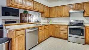A kitchen with wooden cabinets, a stainless steel dishwasher, and a built-in oven. - 12 Mi to Dtwn St Paul: Extended Stay in Woodbury! (Woodbury)