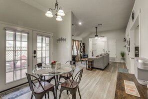 Un grand espace de vie comprenant un coin repas avec une table, des chaises et un canapé. Il y a également un coin cuisine équipé d’une machine à café et d’un réfrigérateur.