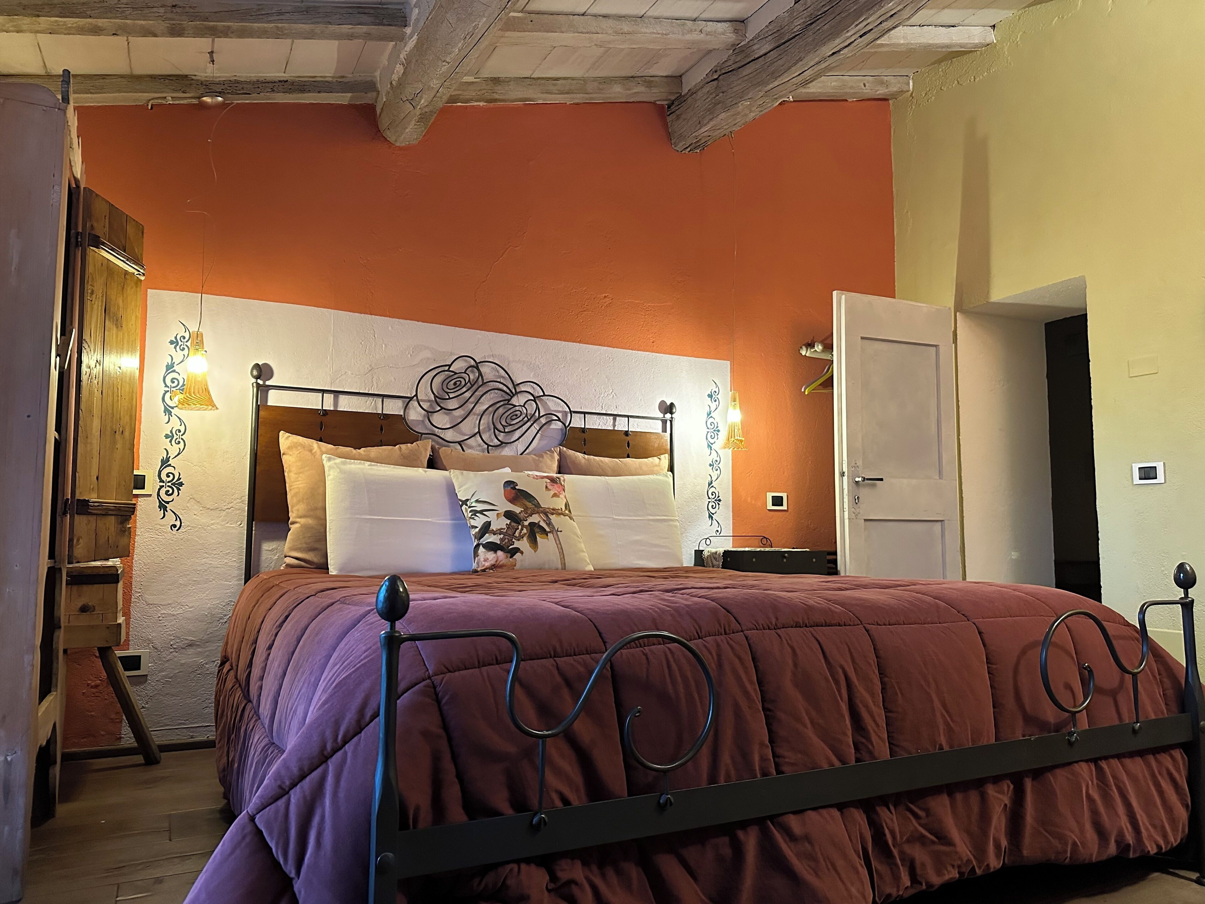 Een slaapkamer met een bed, een houten hoofdbord, decoratieve wandkunst en nachtlampjes.