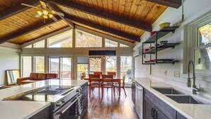 Una cocina amplia con una isla grande, techo de madera y un comedor con mesa y sillas.