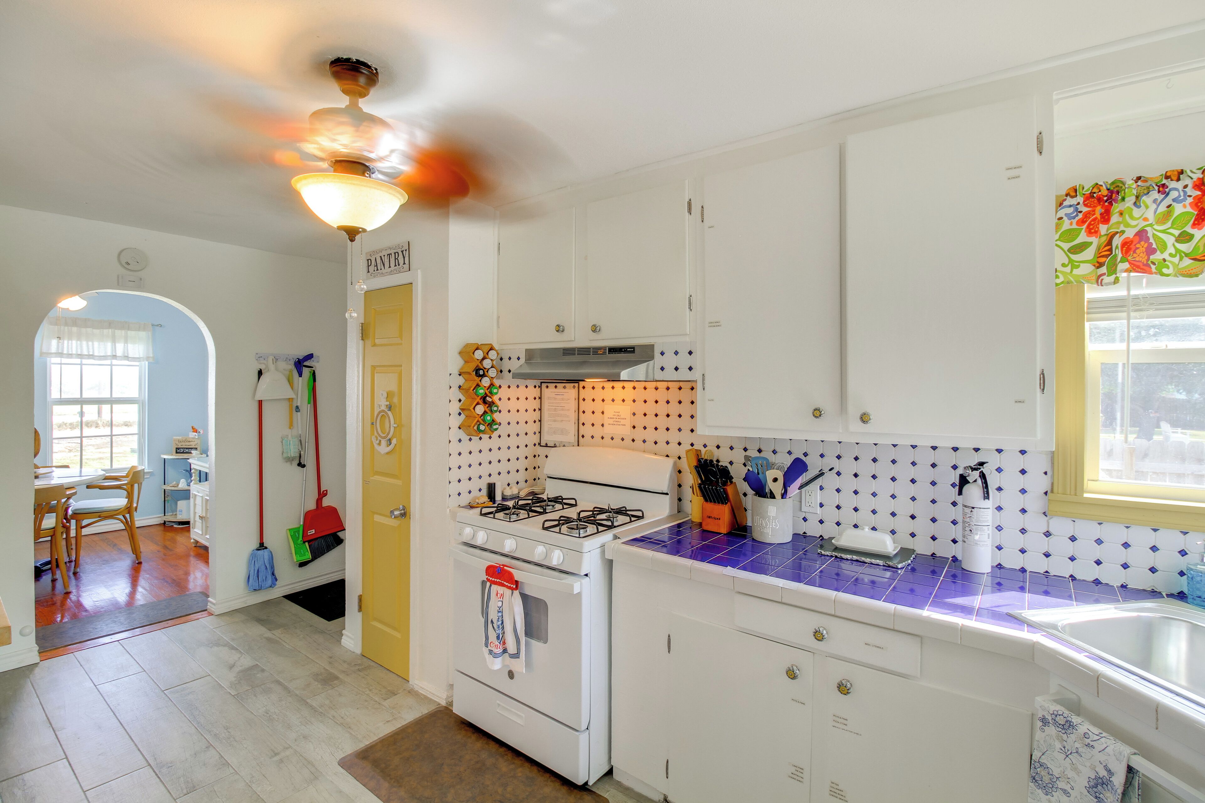 A kitchen with white cabinets, a gas stove, and a blue-tiled countertop.