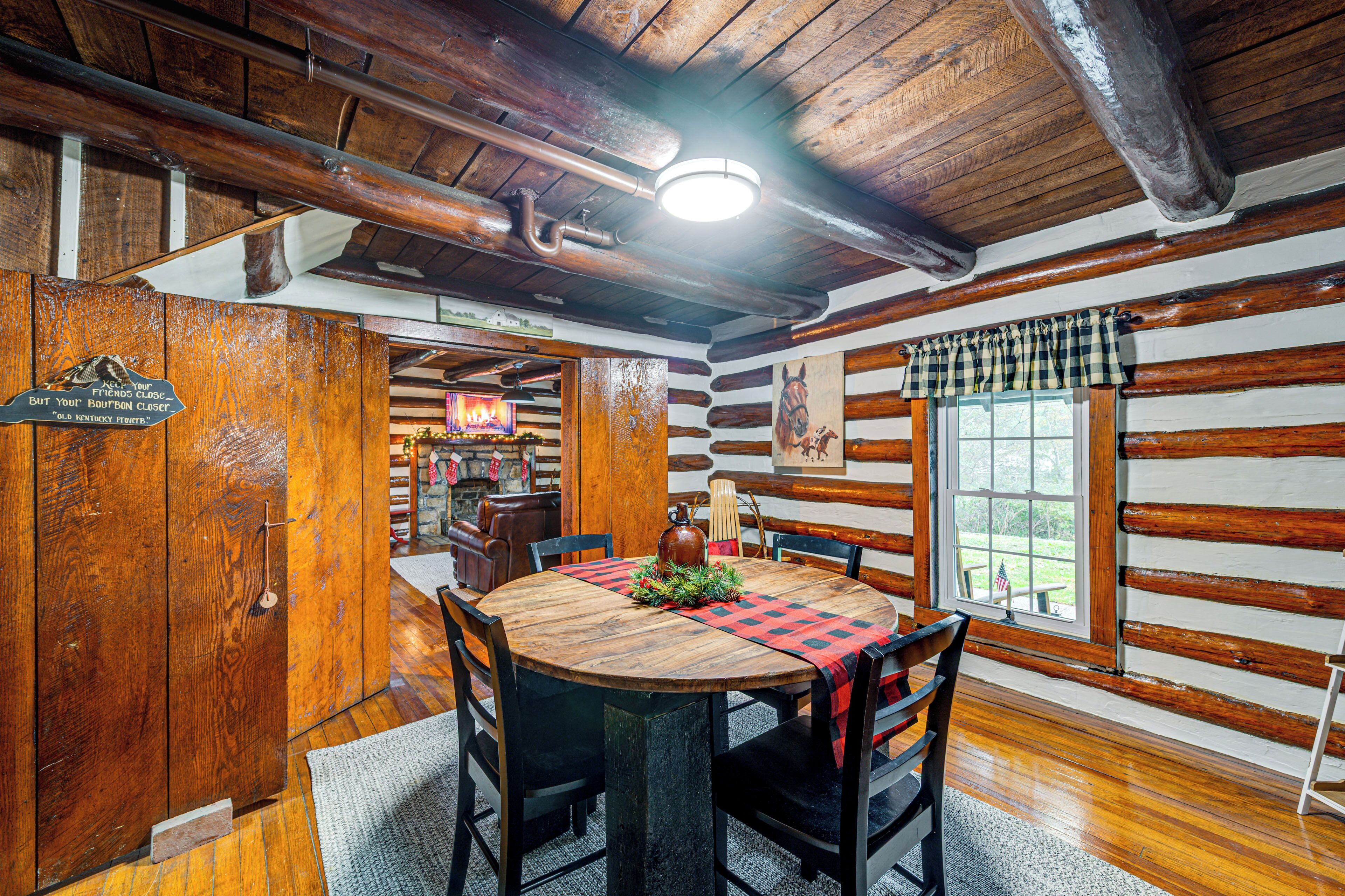 Un intérieur rustique avec des éléments en bois, comprenant une table de salle à manger ronde, des chaises et un plafond en bois avec des poutres apparentes.