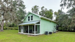 A green house with a porch and a covered patio area. - 1/2 Mi to Sapelo River: Family Home w/ Large Yard (Shellman Bluff)