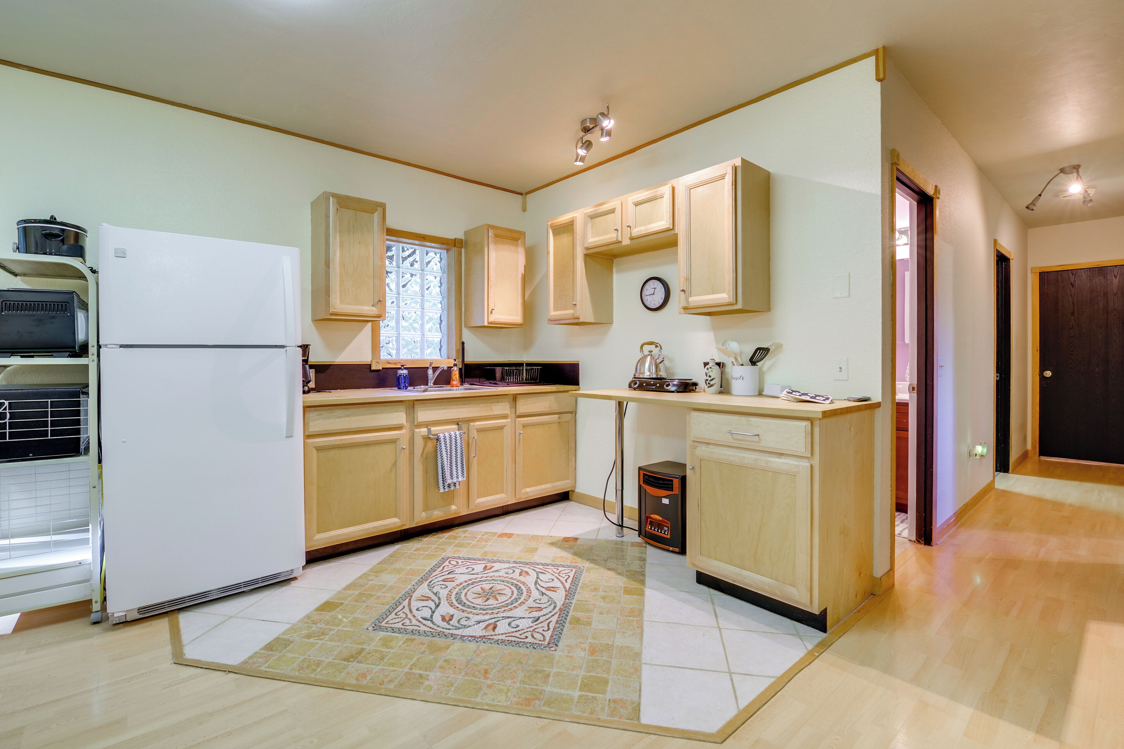 A kitchen with wooden cabinets, a refrigerator, a microwave, and a coffee maker.