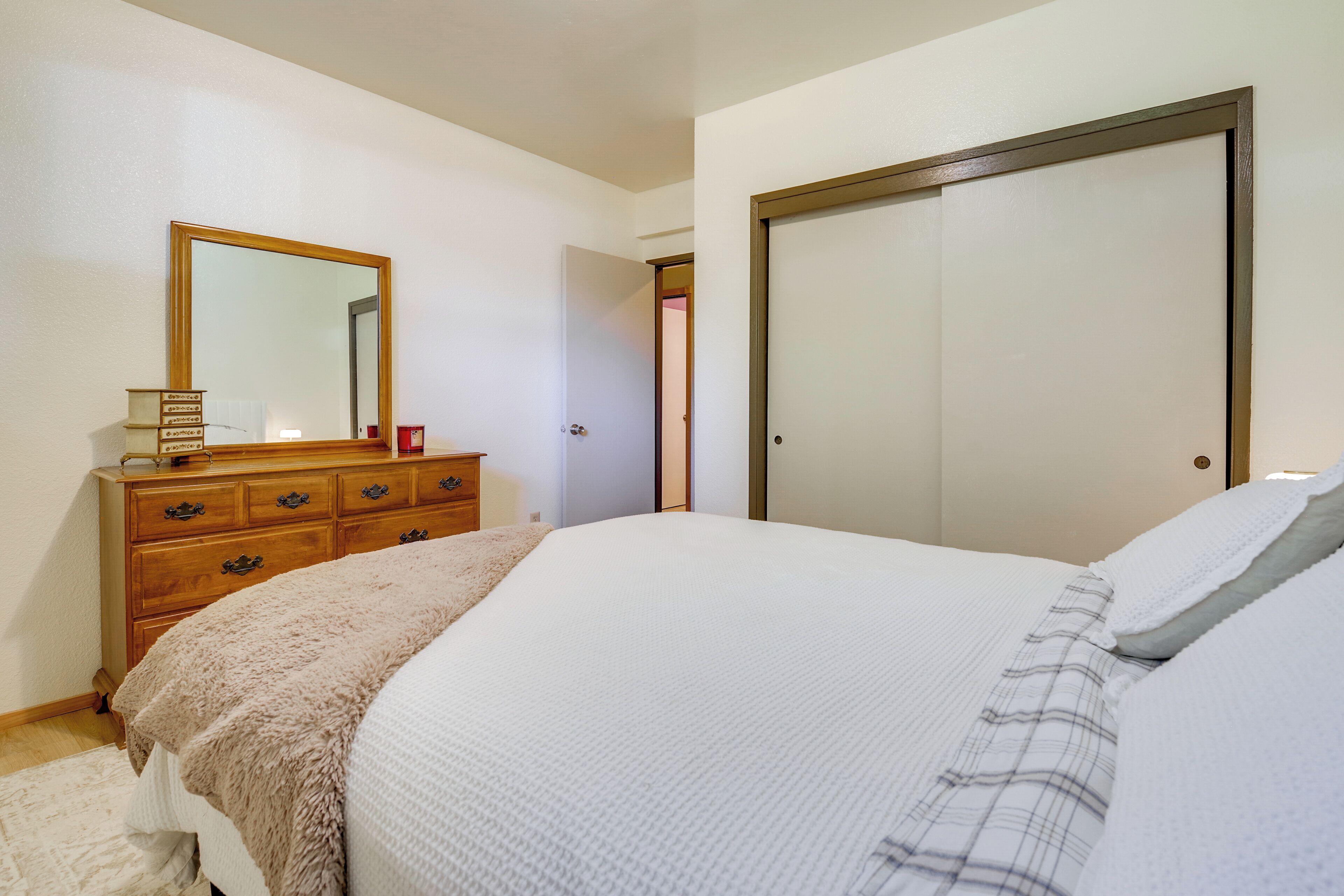 A bedroom with a bed, dresser, mirror, and a door.