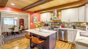 A modern kitchen with wooden beams, white cabinets, and a central island with bar stools. - Ski Asheville! Mountain-View Hideaway w/ Deck (Asheville)