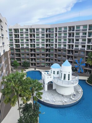 Ein Hotel mit mehreren Etagen, einem zentral gelegenen Schwimmbecken und einer kleinen Insel mit einer weißen Struktur und einer blauen Kuppel.