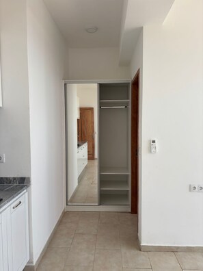 A narrow hallway with a kitchen on one side and a closet with shelves on the other. - JoLi Beach House  - Spacious Second Floor T0 Suite (Santa Maria)