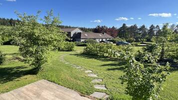 Een woonhuis met een verharde oprit die naar de woning leidt, omgeven door een verzorgd gazon en bomen.