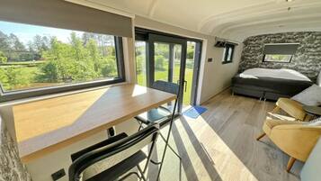 Een compact, modern interieur van een camper met een eethoek, een bed en een groot raam dat een prachtig uitzicht biedt.