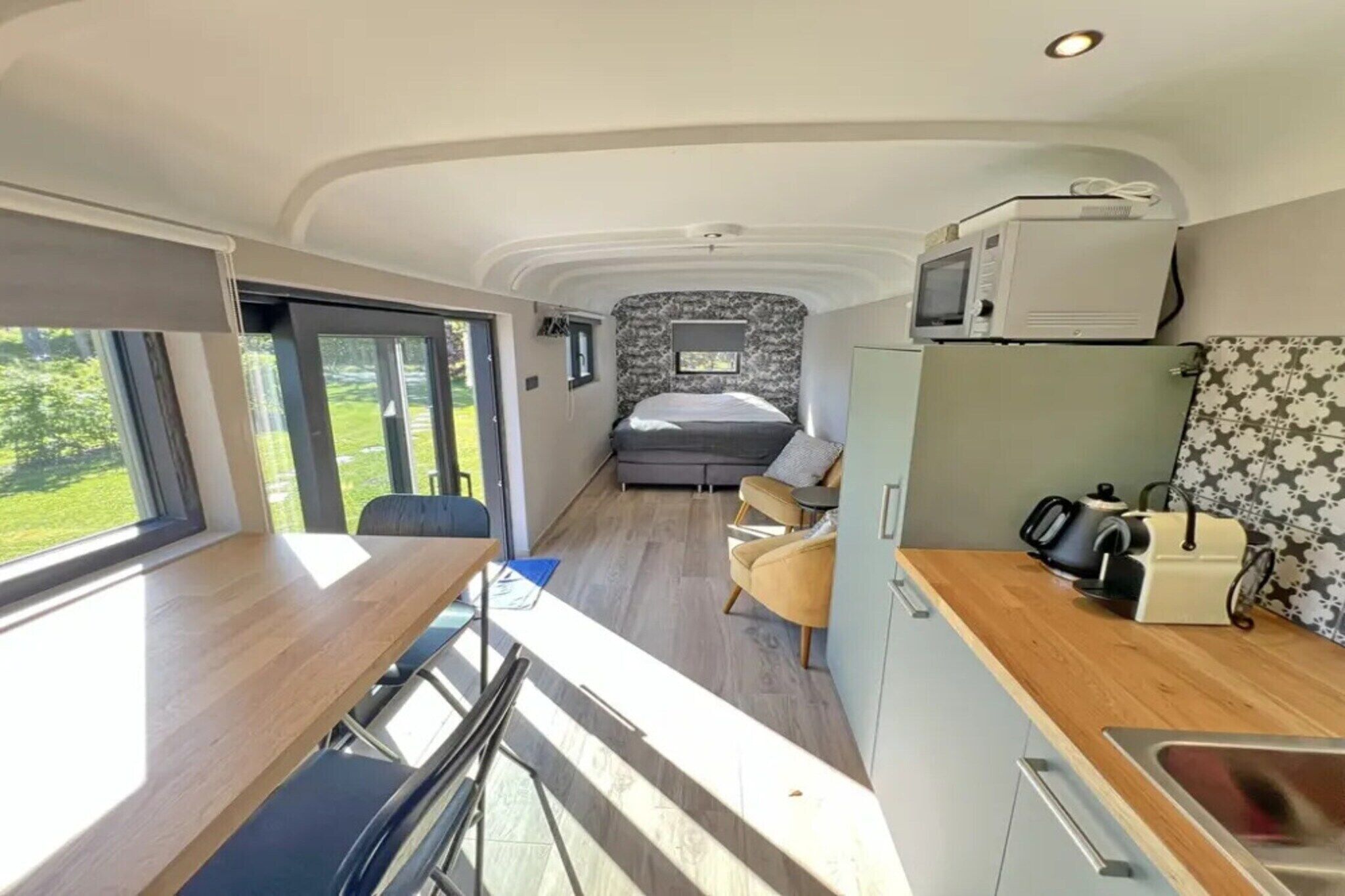 Een compacte camperinrichting met een kitchenette, een bed en een eethoek.