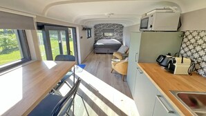 Kompakt indretning i en autocamper med tekøkken, seng og spiseplads.