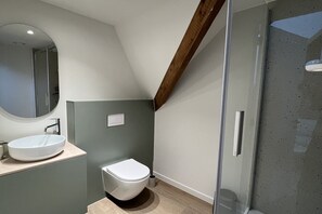 Een moderne badkamer met een ronde spiegel, een wit wastafelmeubel en een toilet.