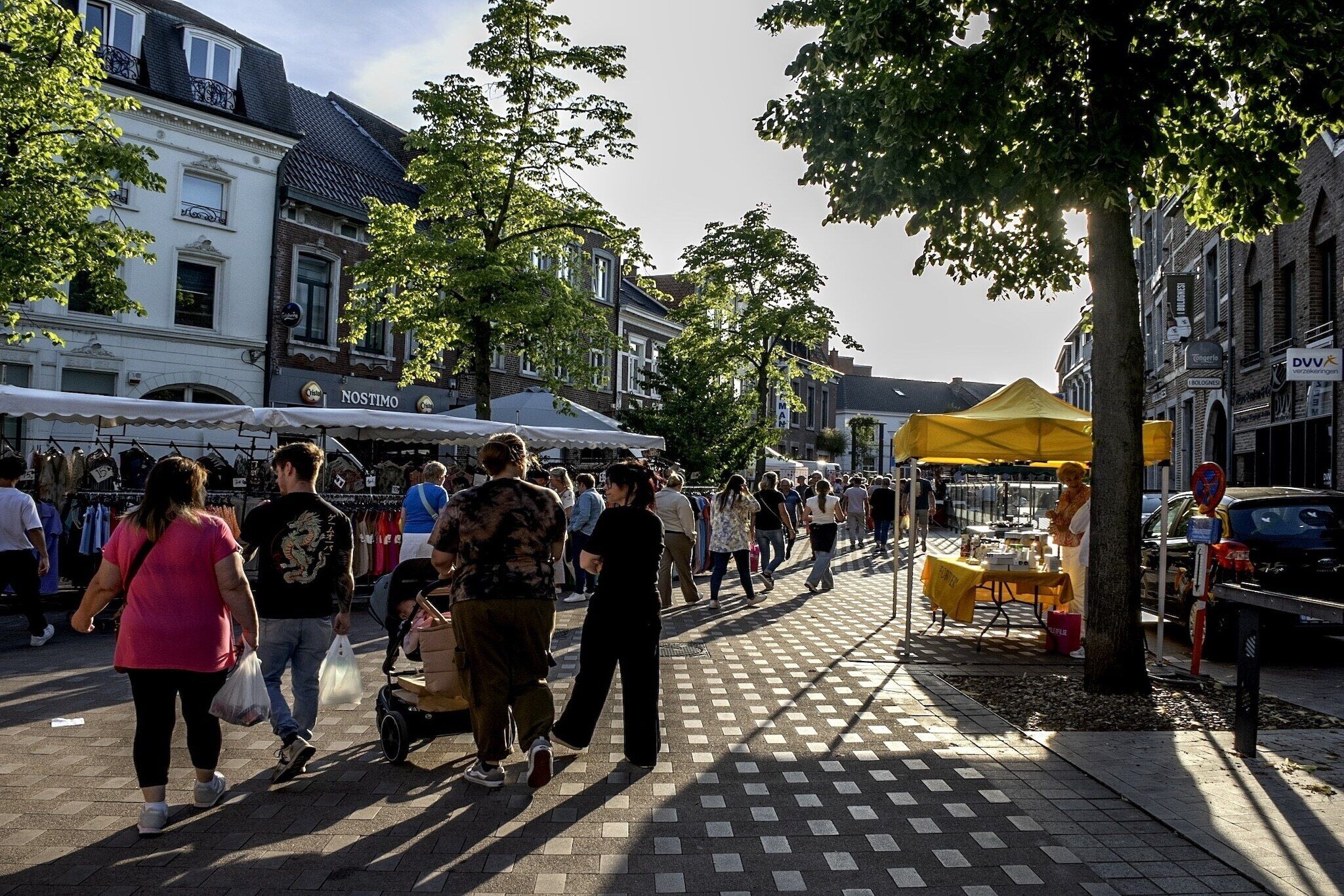 Mercado de rua com pessoas caminhando e vendedores.
