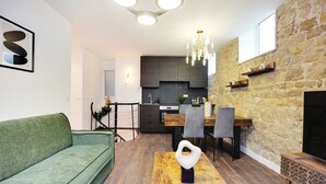 Een moderne woonkamer met een groene bank, een houten salontafel en een eethoek met een houten tafel en stoelen.