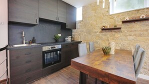 Een moderne keuken met donkere kastjes, een inbouwoven en een eethoek met een houten tafel en stoelen.