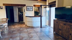 A spacious living area with a wooden dining table, a kitchen in the background, and a large flat-screen TV on a wooden cabinet. - Charming villa with private garden (Alfaz del Pi)