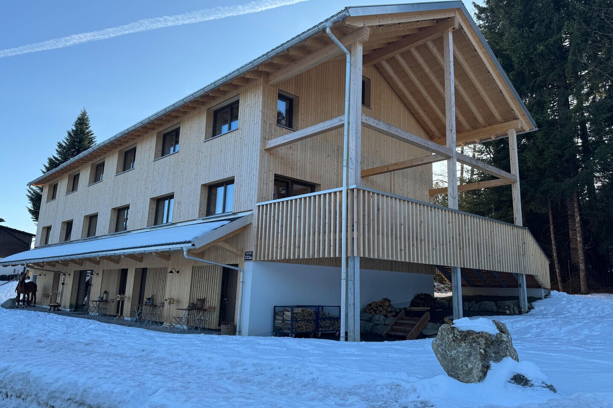 Ein mehrstöckiges Holzhaus mit einer überdachten Veranda und verschneitem Gelände.