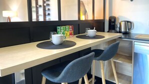 Ein moderner Essbereich mit einem Holztisch, zwei Stühlen, einer weißen Tasse und einer Teedose.
