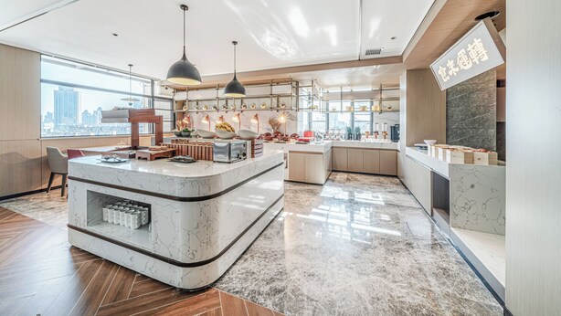 Een moderne keuken met een marmeren aanrechtblad, hanglampen en uitzicht op de stad.
